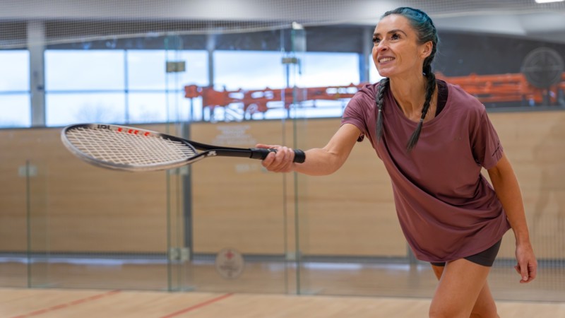 A person smiling playing squash